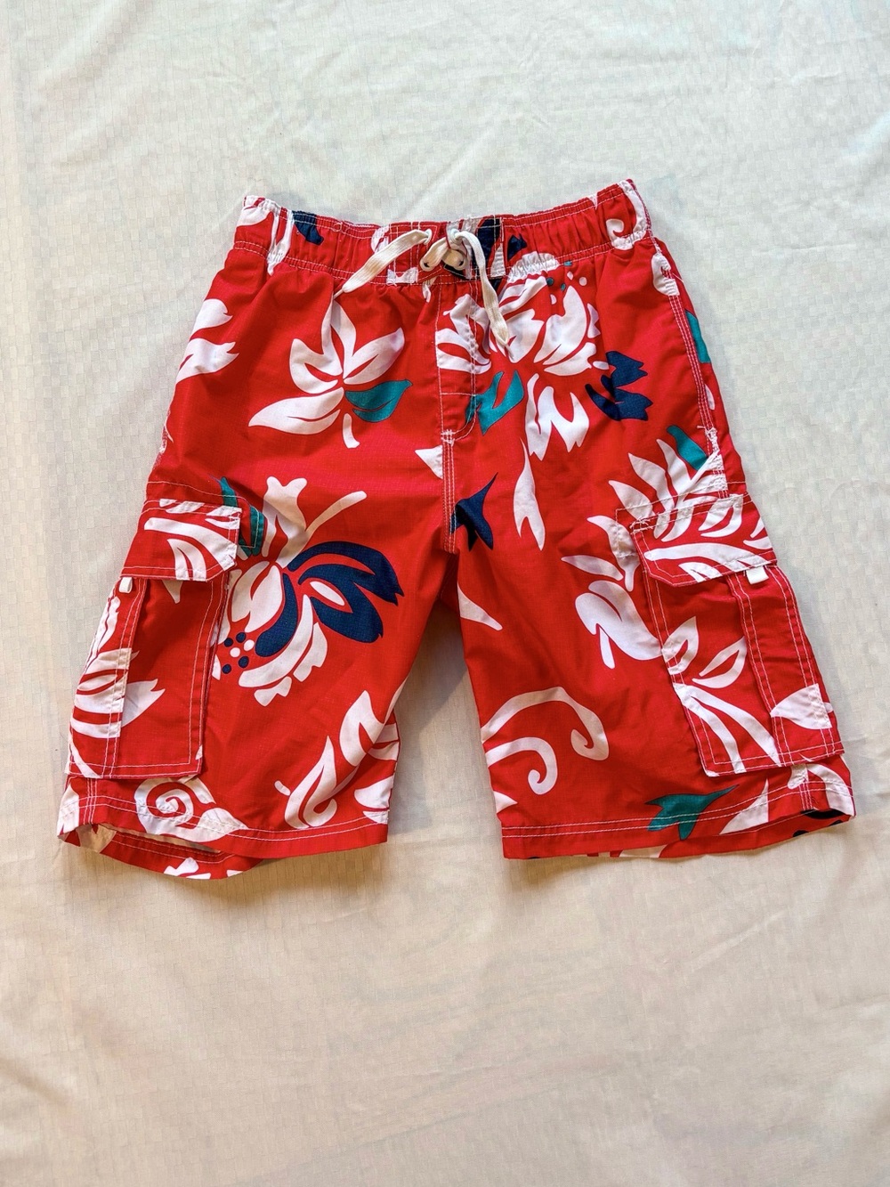 red swim trunks with white and blue tropical print
